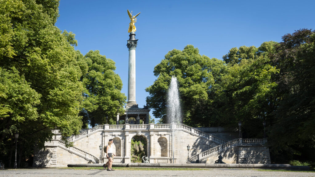 „München ist ein Dorf.“ Diesen Ausspruch hört man immer wieder und auch, dass die Stadt so überschaubar sei, dass man viele Sehenswürdigkeiten zu Fuß erkunden könne. Stimmt das? Auf jeden Fall! Zwei Routenvorschläge für Stadtwanderungen finden sie auf https://www.muenchen.travel/ (https://www.muenchen.travel/artikel/stadt-viertel/stadtwandern-muenchen-nord-sued und https://www.muenchen.travel/artikel/stadt-viertel/stadtwandern-muenchen-ost-west). Eine Stadtwanderung sollte einen unbedingt zum Friedensengel führen. Das 38 Meter hohe Denkmal der griechischen Siegesgöttin Nike ist so etwas wie der Schutzengel der Stadt. Es mahnt zum Frieden – mehr sogar noch als das Pendent in Berlin, das dem Triumph im Deutsch-Französischen Krieg von 1870 und 1871 gewidmet ist. Der Münchner Friedensengel wurde erst später errichtet – in Gedenken an die 25 Jahre Frieden nach diesem Krieg. Genial ist vor allem die Lage: Mitten in den Maximiliansanlagen, einem Park mit mächtigen Bäumen im Stadtteil Bogenhausen, thront weithin sichtbar die goldene Statue auf einer 23 Meter hohen Korinthersäule. Von der großen Aussichtsplattform, der Prinzregent-Luitpold-Terrasse, liegt einem die Stadt zu Füßen: Die Prinzregentenstraße mit ihren Prachtbauten wie dem Bayerischen Nationalmuseum und dem Haus der Kunst bildet eine Sichtachse bis zum Prinz-Carl-Palais. 