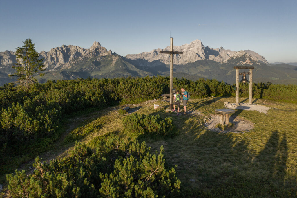 Das achtsame Wandererlebnis - Salzburger Gipfelspiel. Auf dem Bild sieht man ein Wanderpärchen vor dem Gipfelkreuz am Gerzkopf.